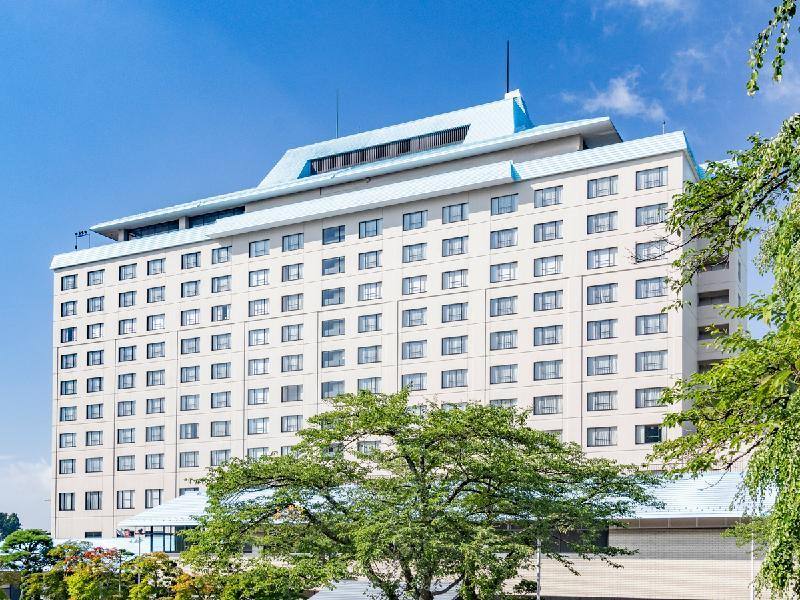 Hotel Senshukaku rising above trees under a blue sky