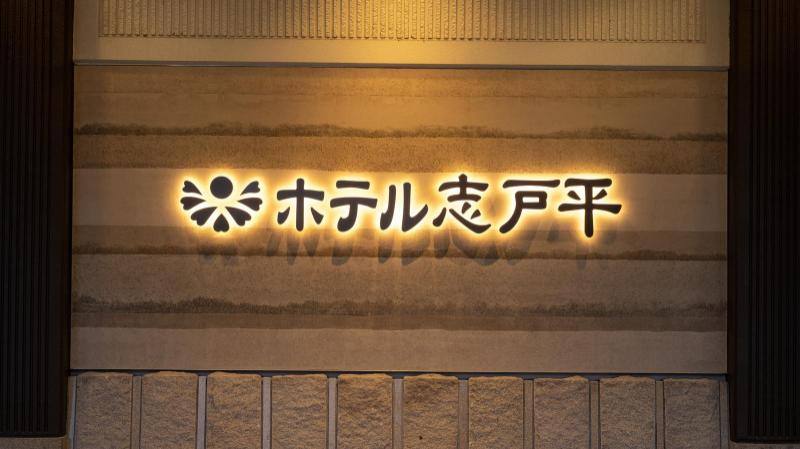 Illuminated Hotel Shidotaira sign on a stone wall