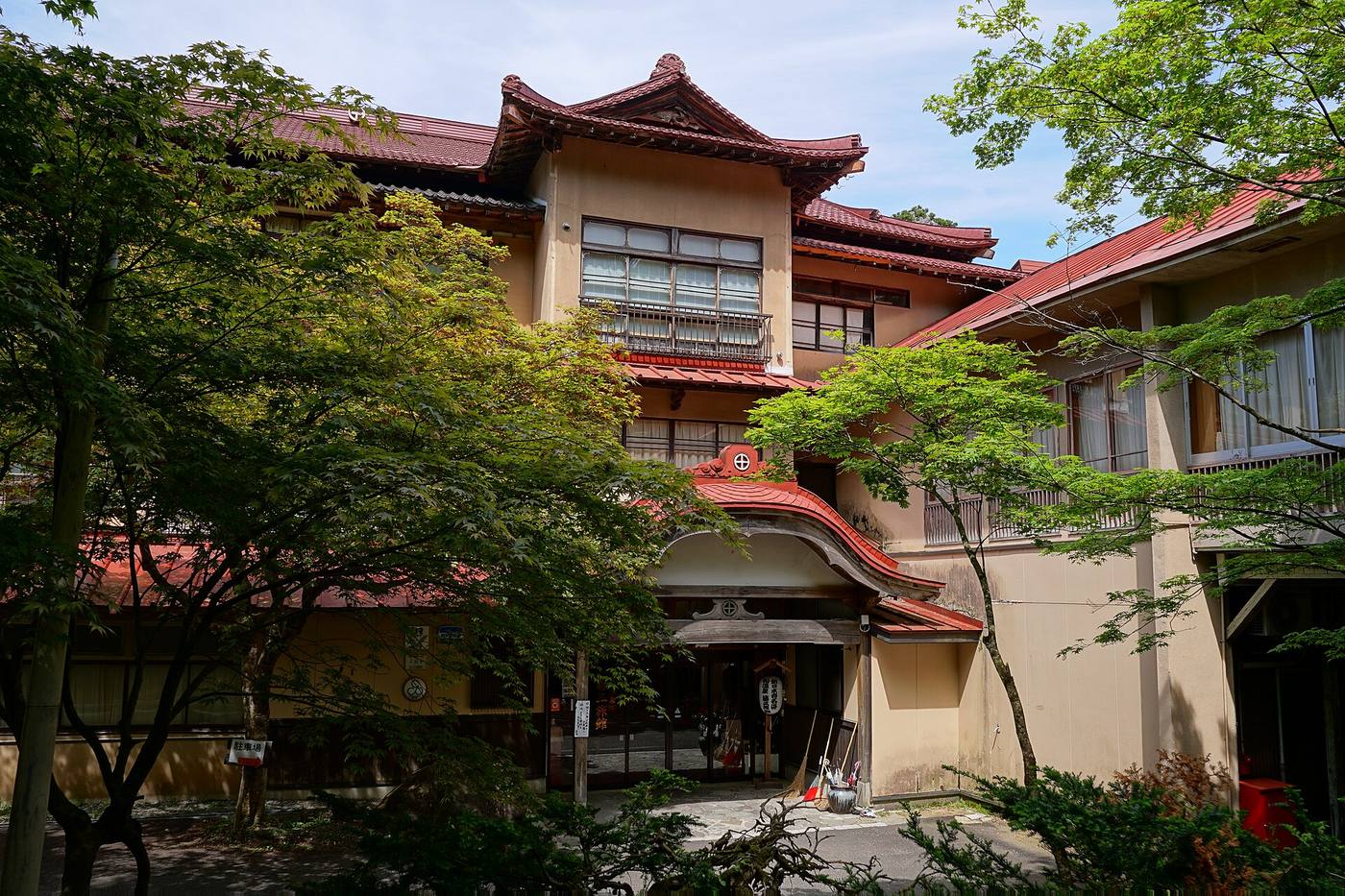 Fujisan Ryokan at Namari Onsen, with its red-roofed wooden facade and trees.