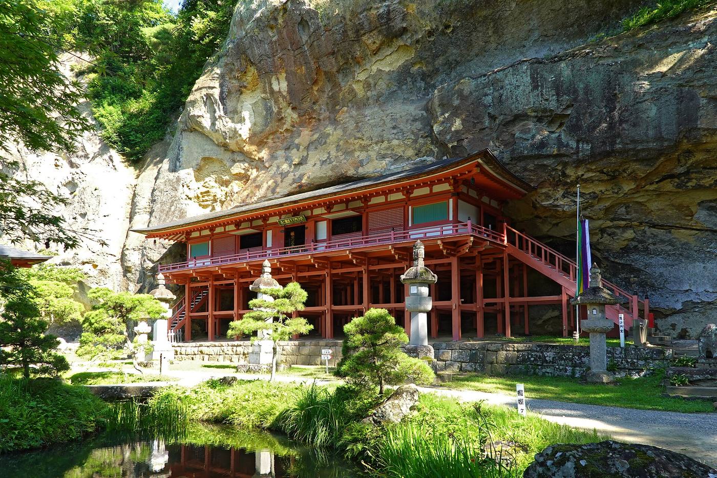 The red Bishamondo hall of Takkoku no Iwaya built against the rock cliff.